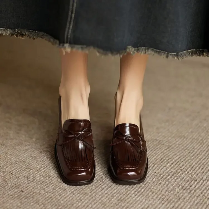 Front view of brown patent tassel loafer pumps on feet