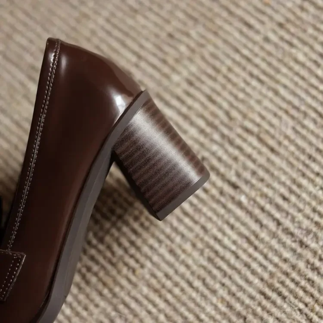 Close-up of stacked block heel on brown patent leather loafer