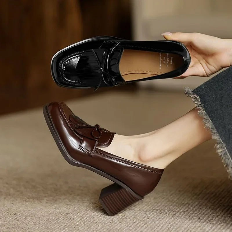 Black and brown patent tassel loafer pumps shown side by side