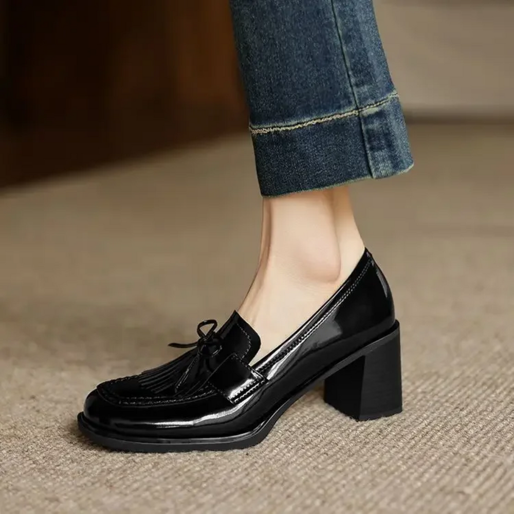 Side view of black patent tassel loafer with block heel