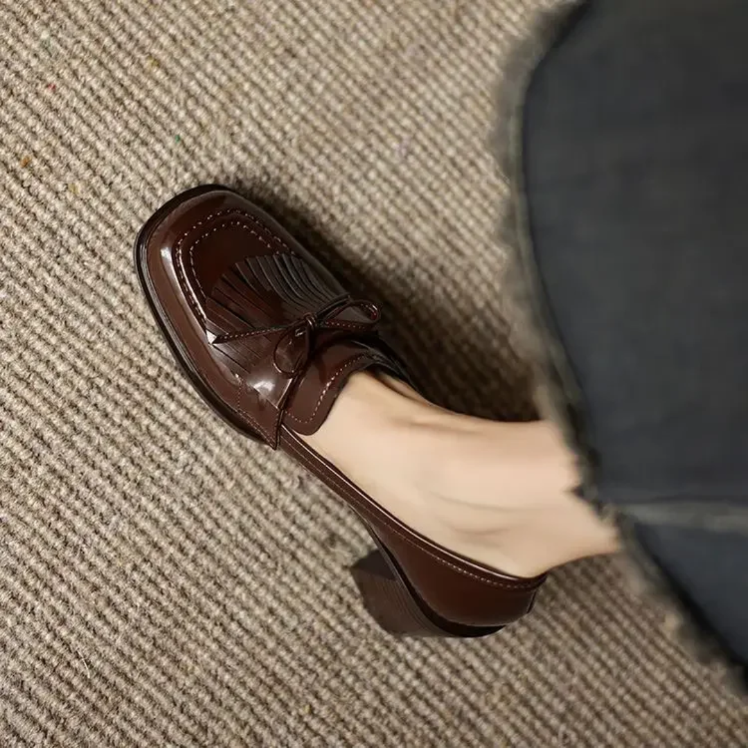 Close-up of brown patent loafer toe with bow tassel detail