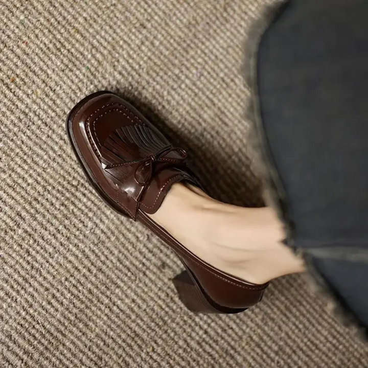 Close-up of brown patent loafer toe with bow tassel detail