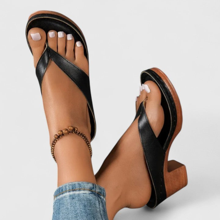 Black leather thong sandals with chunky wood-style block heel, worn on feet