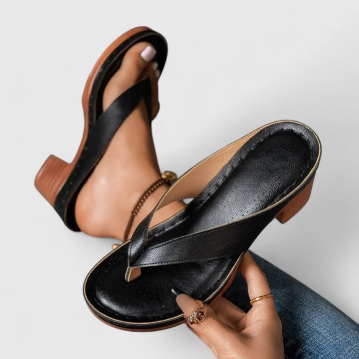 Black thong sandal held by hand, showcasing platform sole and block heel