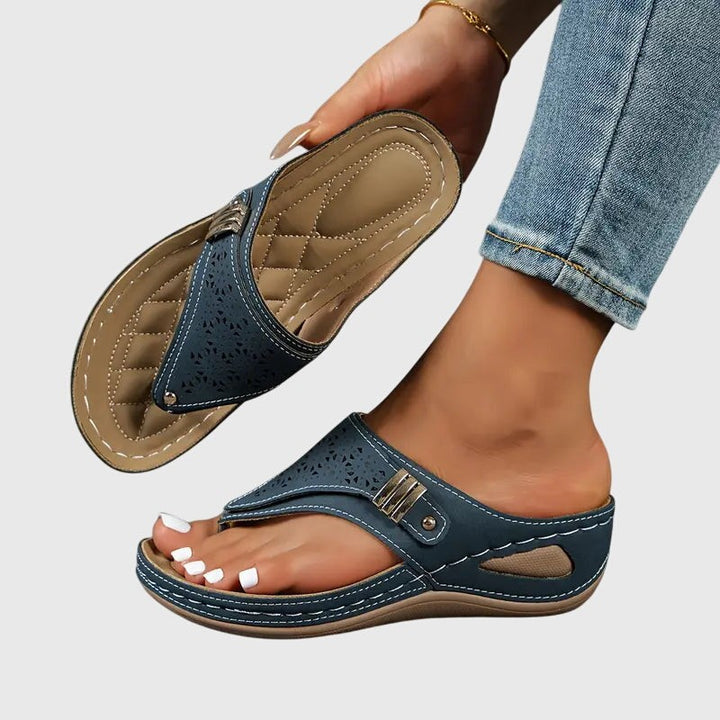 Navy blue wedge sandal featuring perforated design and cushioned quilted insole
