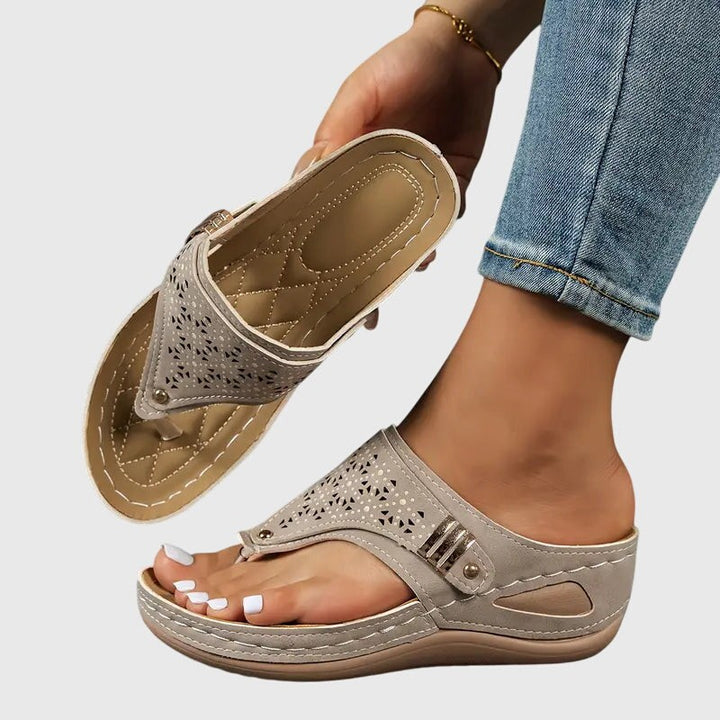 Gray perforated wedge sandal showing arch support and buckle strap accent