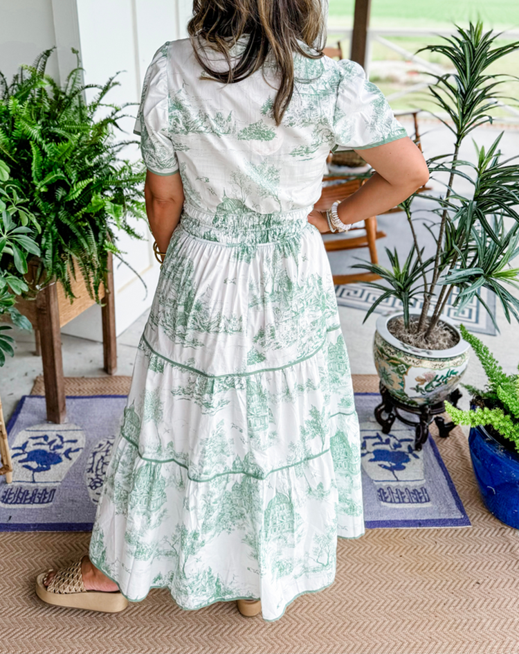 Back view of green toile maxi dress showing smocked waist and tiered hem