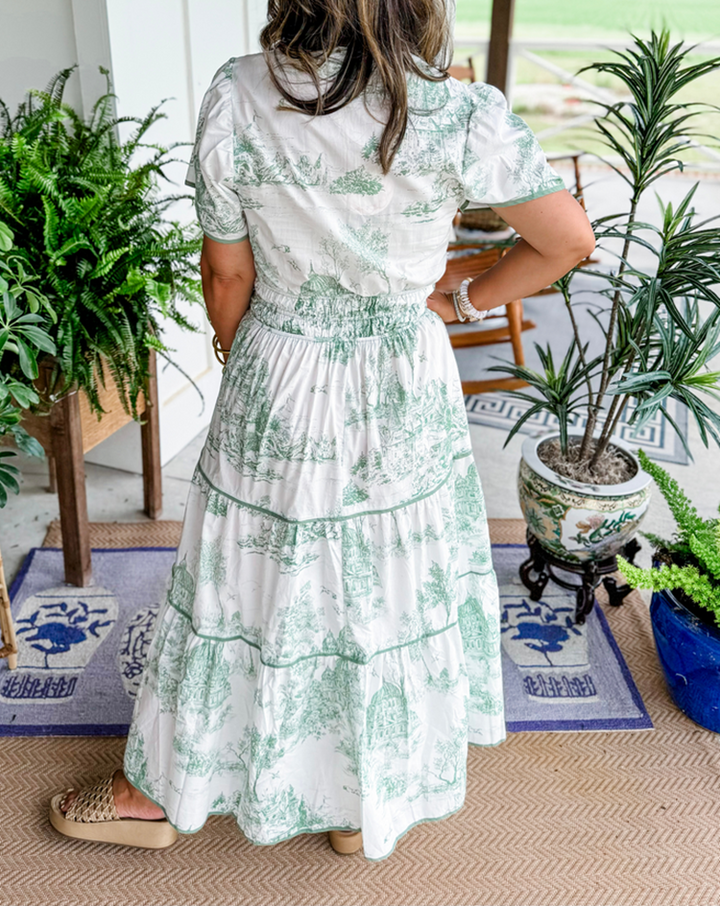 Back view of green toile maxi dress showing smocked waist and tiered hem