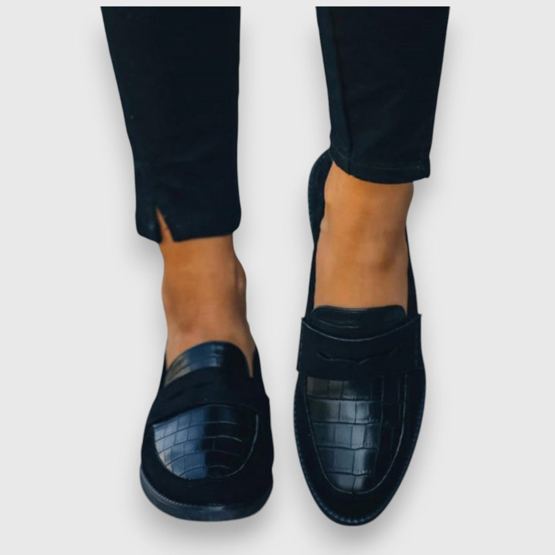 Top-down view of black suede loafers with embossed crocodile leather accent