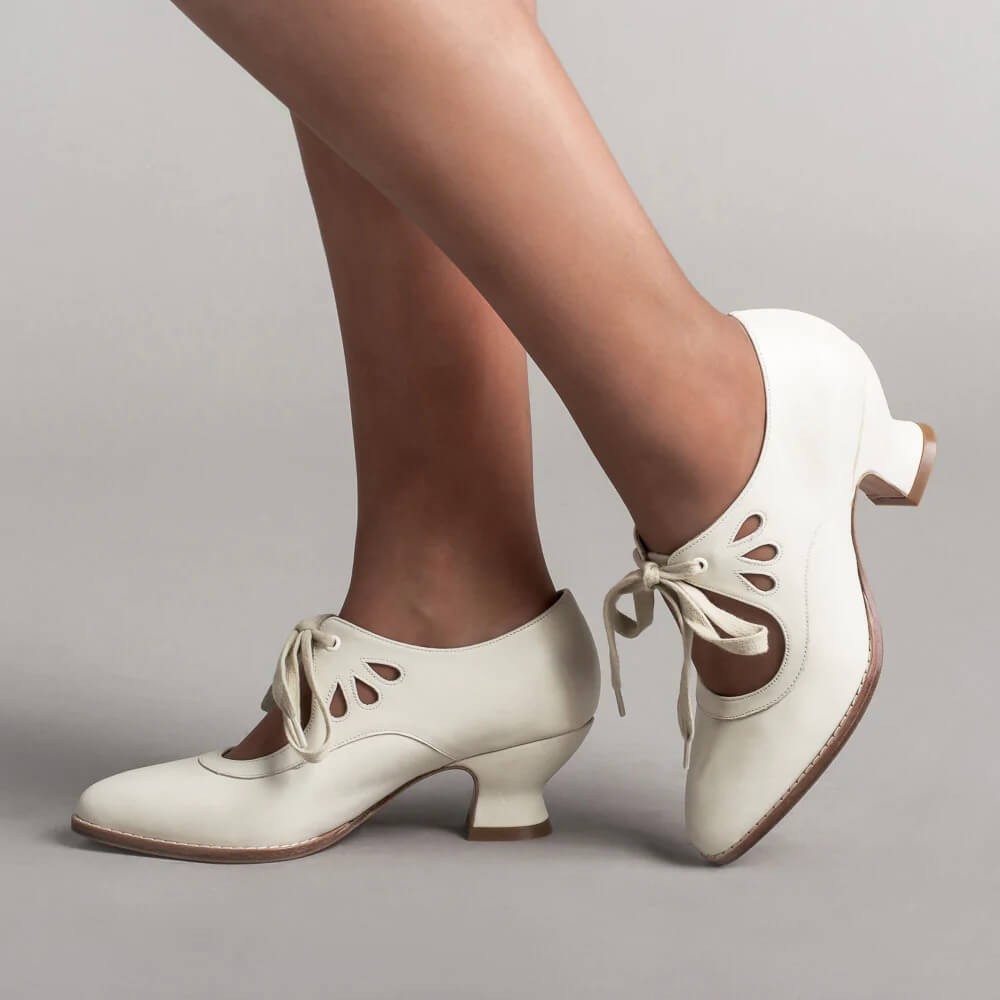 ivory leather lace-up pumps with teardrop cutout detail, modeled on feet