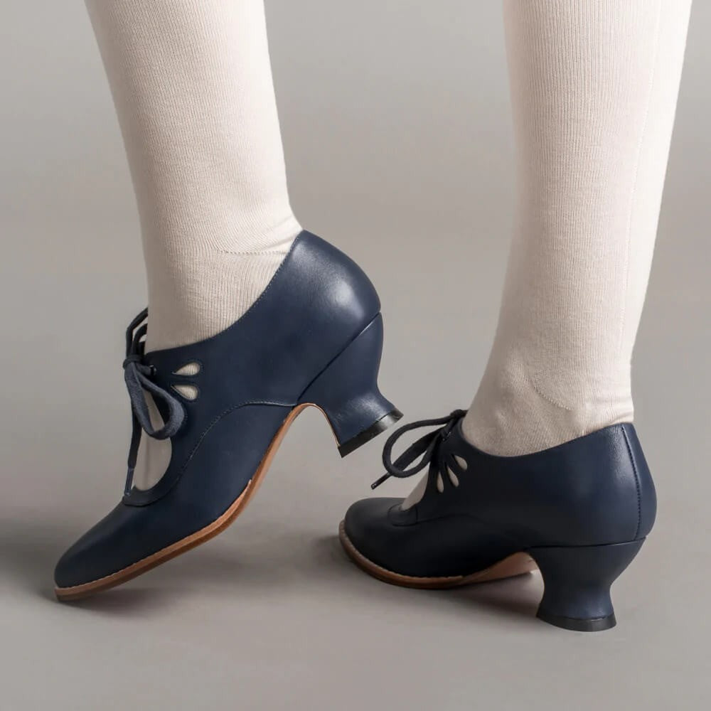 navy blue lace-up heels with teardrop cutouts, shown from behind on feet