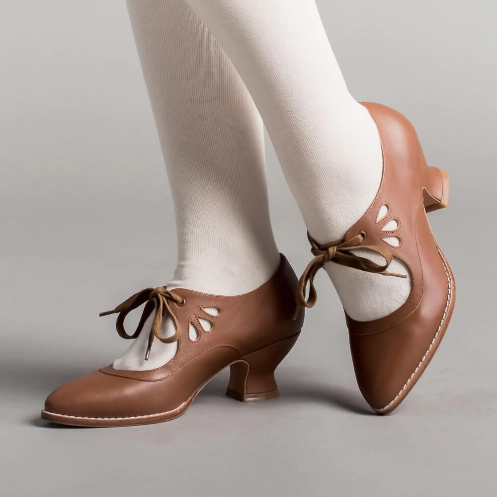 cognac brown leather pumps with lace-up detail, worn on feet