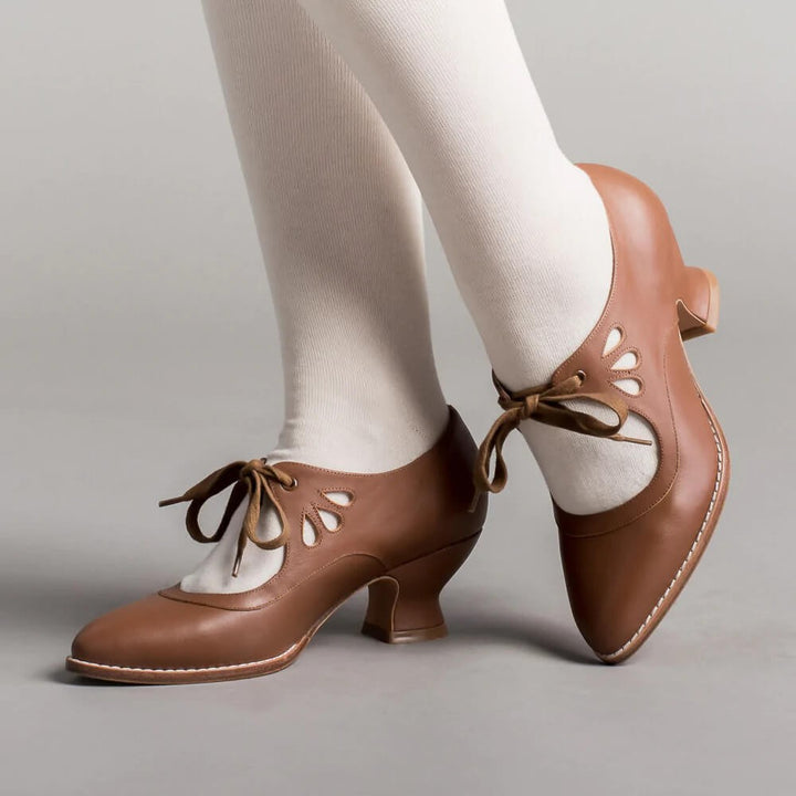cognac brown leather pumps with lace-up detail, worn on feet