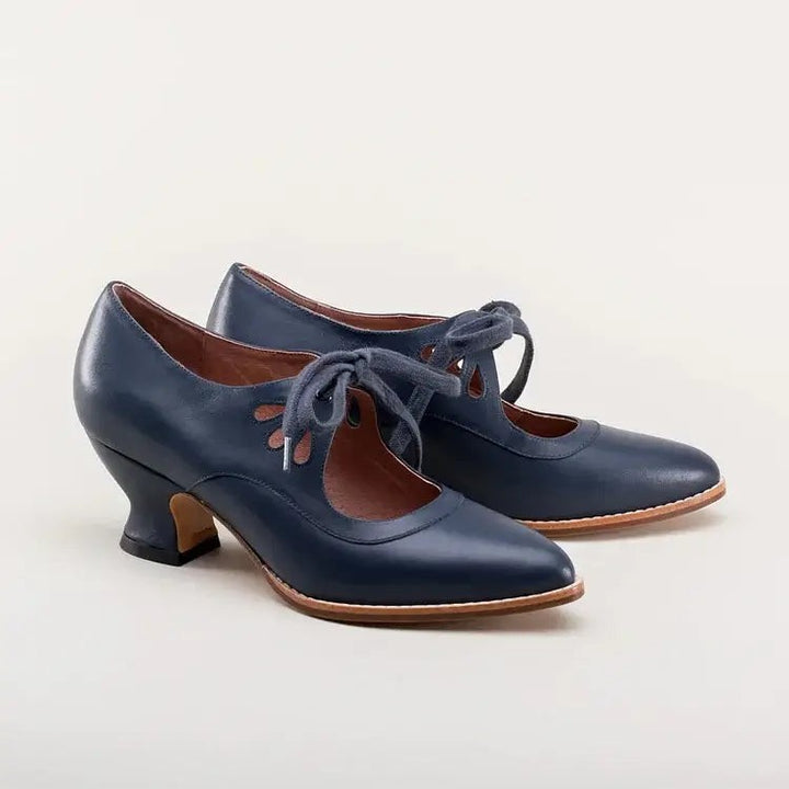 navy blue leather pumps with teardrop cutouts and curved heel, studio shot