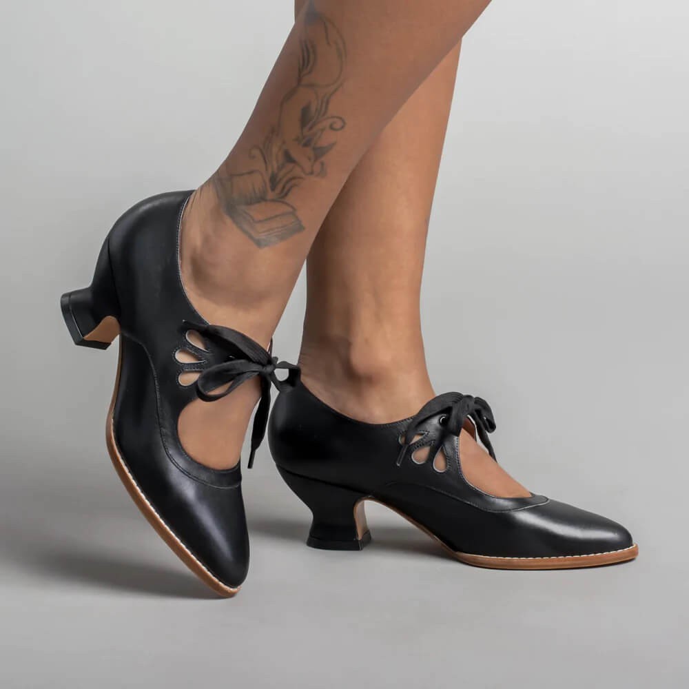 black leather lace-up heels with teardrop cutouts, worn on model