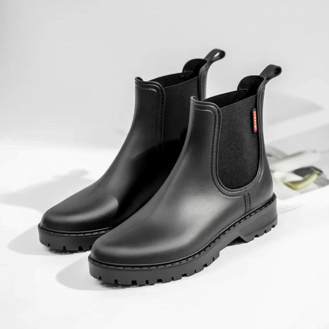 Pair of black insulated Chelsea boots displayed on light textured background