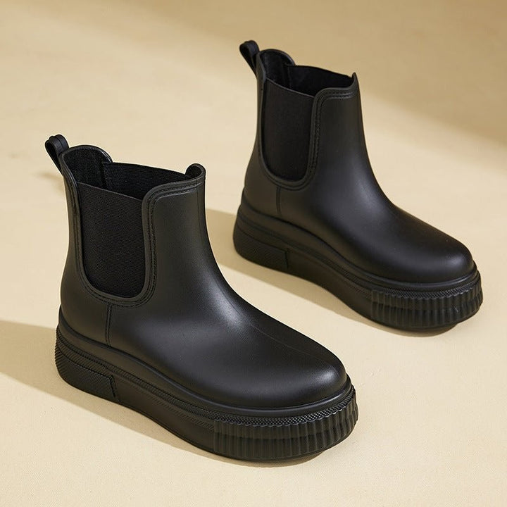 Black Chelsea rain boots featuring thick platform sole and pull-tab heel