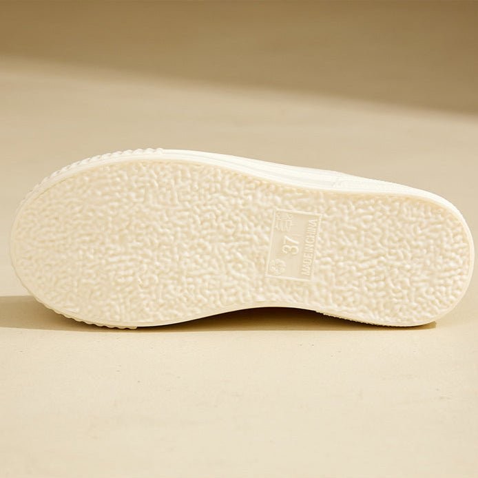 Bottom view of cream rain boot showing ribbed rubber tread pattern