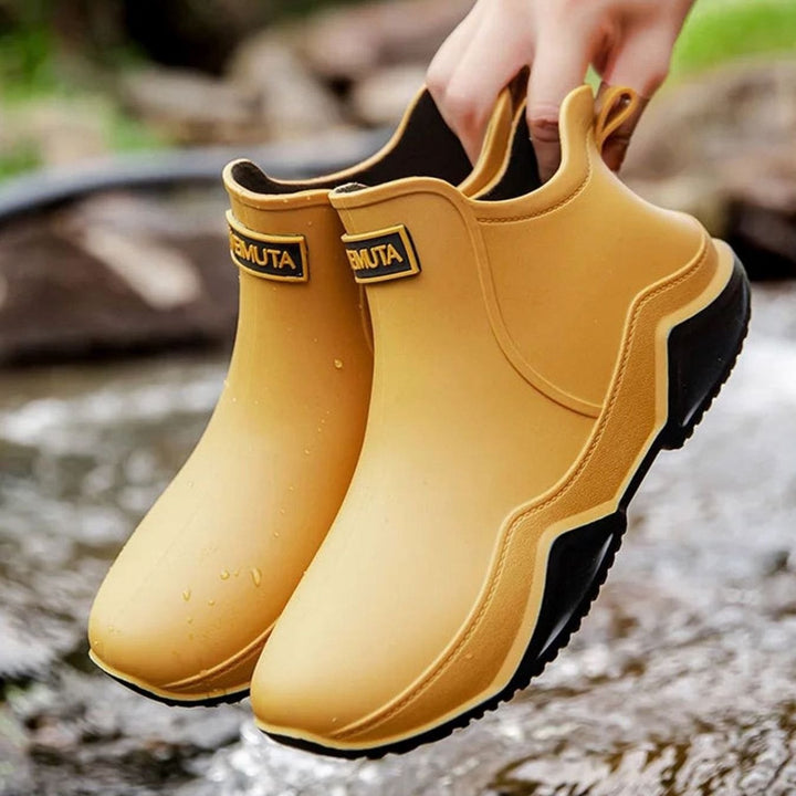 Mustard yellow waterproof ankle boots with black sole, held above water