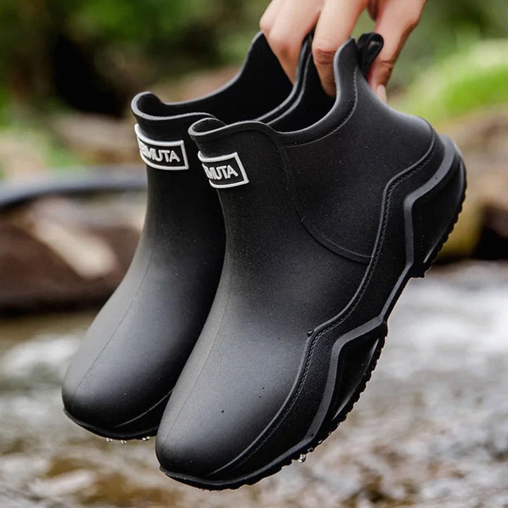 Black waterproof ankle boots with subtle tread sole, dangled outdoors