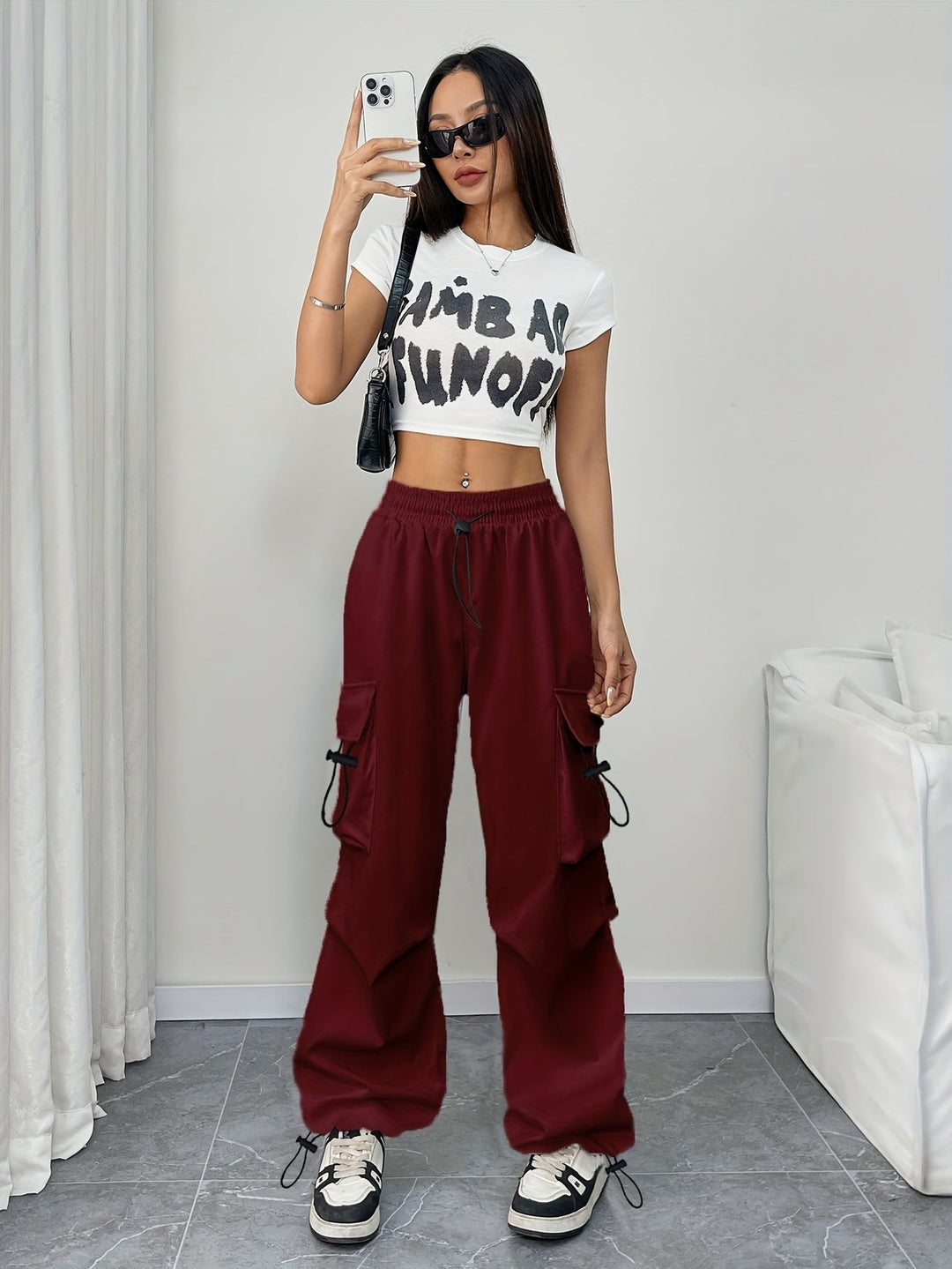 Model wearing burgundy cargo pants with white crop top and sneakers