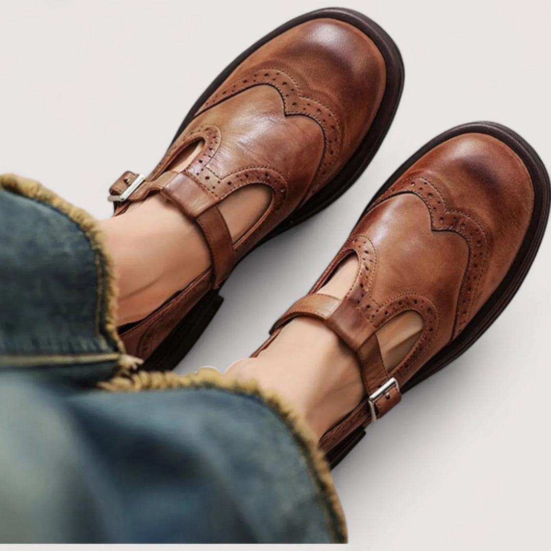 Brown leather Mary Jane shoes with wingtip brogue detailing and buckle strap