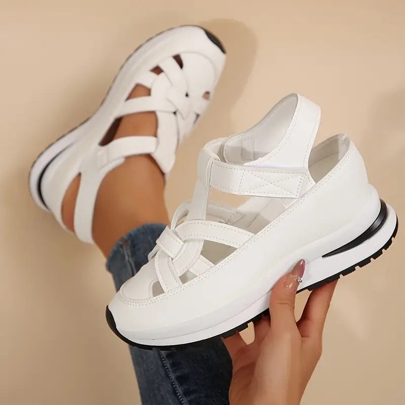 white orthopedic sandals with woven front strap and black platform sole, held in hand