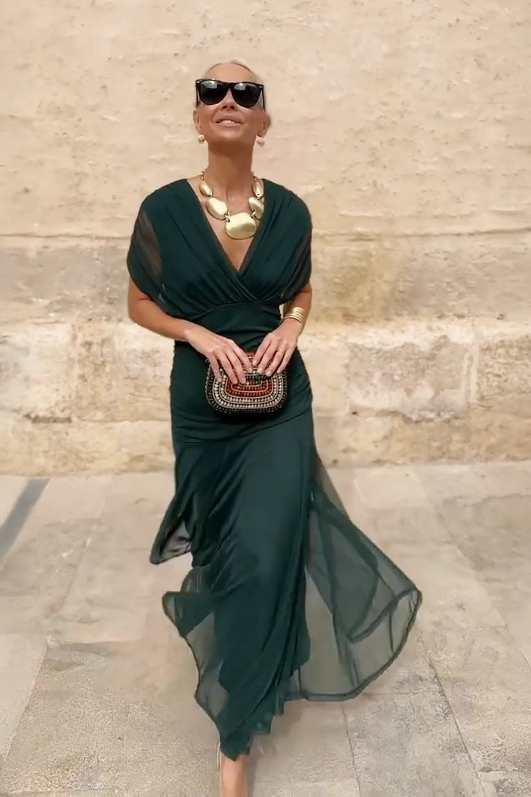 Front view of ruched emerald maxi dress with wrap V-neckline and beaded clutch